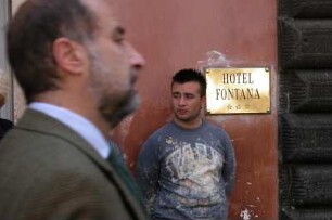 Rom - Bauarbeiter beobachtet Touristen : Ein Bauarbeiter lehnt an einer Hauswand des Hotels "Fontana" und beobachtet Touristen am Trevi-Brunnen in Rom, ein Geschäftsmann geht vorbei, aufgenommen im April 2004
