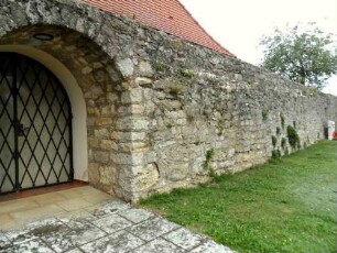 Kirchhof im Nordwesten-Kirchhofmauer mit neuzeitlichem Tor (außenseitig Bahrhaus und Kapelle)-auf der Mauerkrone Ansatz der Steinbrüstung erhalten (Wehrgang im 18 Jh abgetragen)
