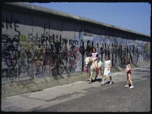 Berlin-West. Kreuzberg, Grenzanlage Berliner Mauer. Bemaltes Mauerstück mit Kindern davor