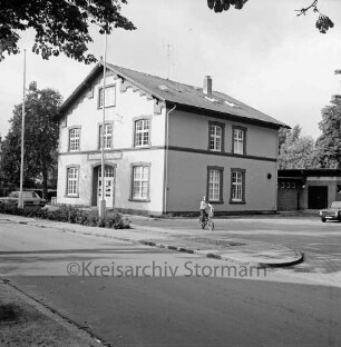 Jugendfreizeitstätte: am Bürgerpark: Einweihung: Außenaufnahme: davor Straße, Verkehrsinsel mit zwei Fahnenmasten, Kind auf Fahrrad, Pkws: rechts Garage: oben überhängende Zweige von Baum