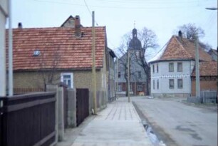 Dorfstraße, Häuser, Kirche im Hintergrund