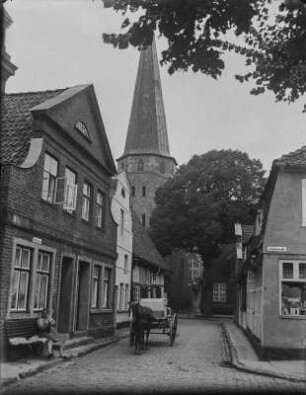Gasse in Travemünde : Fuhrwerk in einer Gasse, dahinter St. Lorenz Kirche