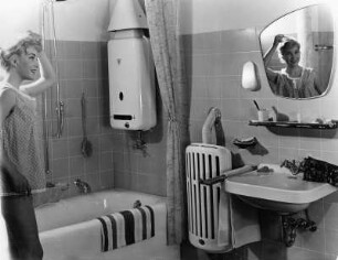 Werbefotografie für die Hamburger Gaswerke. Eine Frau steht im Bad, dass von einer Gasheizung beheizt wird. Warmwasser erhält sie durch eine Gastherme