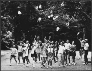 Schulkinder, Mützen in die Luft werfend