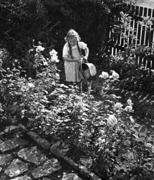 Kinderbilder. Mädchen mit Gießkanne in einem Garten in Bayreuth