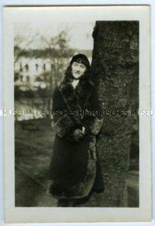 Herta Fleischhut im Pelzmantel an einen Baum gelehnt