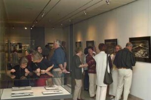 Ausstellungseröffnung. Besucher betrachten ausgestellte Fotografien