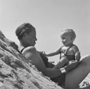 Frau in Bademode und Kleinkind am Strand