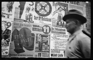 Mann vor einer Hauswand mit Wahlplakaten verschiedener Parteien anlässlich der Landtagswahlen am 12.Mai 1929