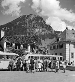 Bad Hindelang. Straßenbild mit Busreisenden. Blick zum Hirschberg
