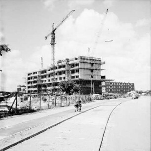 Poppenbütteler Straße: vorne Parplatzflächen, links eine Baustelle, Rohbau eines Wohngebäudes des Heußweges, dahinter Wohngebäude der Segeberger Chaussee: Blick nach Nordwesten