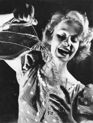 Das Modell Eva Roscher gießt Wasser aus einer Karaffe in ein Glas. Aufnahme für einen Prospekt der Hamburger Wasserwerke aus dem Jahr 1956