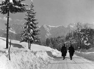 Winterbilder. Zwei Spaziergänger auf freigefräster Straße bei Garmisch (heute Garmisch-Partenkirchen)