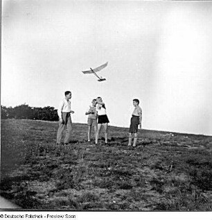 Jungengruppe beim Ausprobieren eines Segelflugzeugmodells an einem Hang