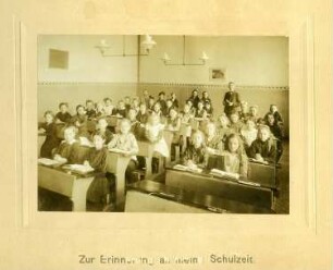 Gruppenaufnahme einer Mädchenklasse mit ihrem Lehrer. Aufnahme im Klassenzimmer, um 1900/1910