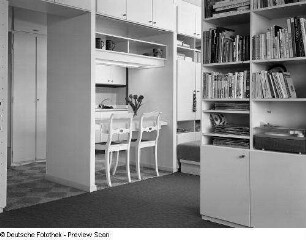 Mustereinraumwohnung (1972; Deutsche Bauakademie). Ansicht mit Arbeitsecke und Bücherschränken als Raumteiler. Blick zur Küchenecke