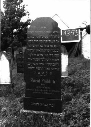Grabstein 1353 (Index: 100104666) Material: schwarzer Granit Zustand: gut erhalten Maße HxBxT: 125x46x17 cm Beschreibung: Stele auf getrepptem Sockel, Dreiecksabschluss mit seitlichen Einzügen und abgeflachter Spitze: Grabstein 1353