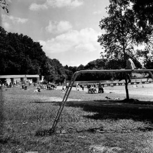 Badeanstalt: am Herrenteich: Liegewiese am Ufer, Badegäste: Badesteg: hinten links Umkleideräume: im Hintergrund Wald: im Vordergrund Kind auf Klettergerüst
