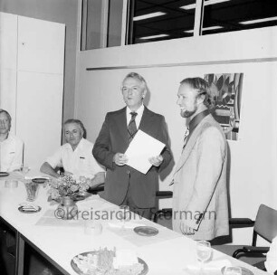 Schulzentrum Am Heimgarten: Reesenbüttler Redder: Ernennung von bisherigem kommissarischem Leiter der Realschule Klaus Guttenberger zum Direktor der Realschule durch Schulrat Wilhelm Strech, mit Urkunde in Hand: am Tisch im Beisein von Rektor der Hauptschule Horst Kühne: Gläser, Snacks, Blumenschmuck