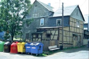 Haus mit mehreren Anbauten; davor Containerstellplatz