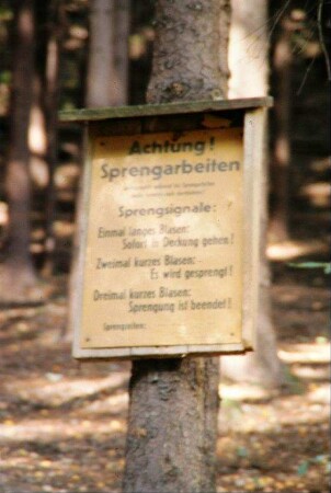 Schild an einem Fichtenstamm "Achtung Sprengarbeiten ..."