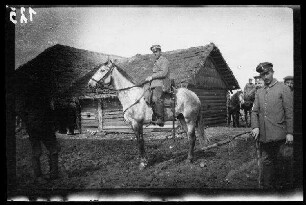 bei Wirballen (?) (=Virbalis, Litauen): "schwerer Reiter" zu Pferd vor einem landwirtschaftlichen Holzhaus mit Reetdach