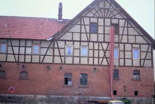 Haus mit Kreuzdach, Wohnhaus und Stallgebäude, Feuerwehrschläuche hängen aus einem Bodenfester