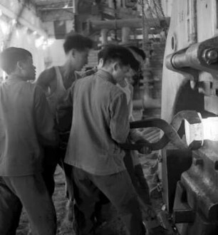 Gruppe von Arbeitern an einer Schmiedepresse