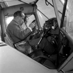 Pilot (unbekannter Landrat) am Cockpit eines Kleinflugzeuges