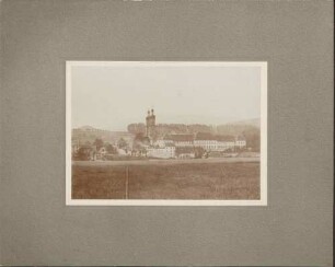 Kirche und Kloster, davor rauchende Häuserruinen.
