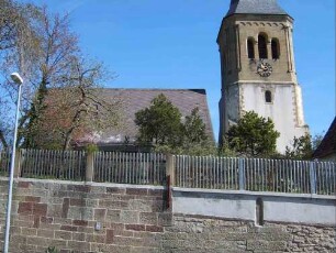 Ansicht von Süden mit Kirche (Kirchturmuntergeschoß Romanisch - Obergeschoß Neuromanisch - Langhaus Neubau 1969) über Kirchhofmauer (Wehrgang 1864 abgetragen)