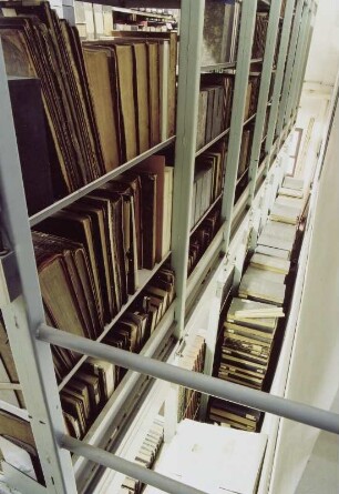 Sächsische Landesbibliothek - Staats- und Universitätsbibliothek Dresden. Zentralbibliothek (ehem. Landesbibliothek). Erdgeschoss (Flachbau). Abteilung Benutzung, Magazin. Blick vom aufgeständerten Zwischenboden nach unten auf gestapelte Bestände : Dresden-Neustadt, Marienallee 12. Sächsische Landesbibliothek - Staats- und Universitätsbibliothek Dresden. Zentralbibliothek (ehem. Landesbibliothek). Erdgeschoss (Flachbau). Abteilung Benutzung, Magazin. Blick vom aufgeständerten Zwischenboden nach unten auf gestapelte Bestände