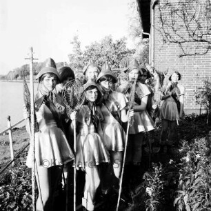 Karpfenfest: Herrenteich: im Vorwege des Festspiels: Fischerinnengarde mit Keschern in Ufergarten: rechts Hausecke: links Geländer, Pfahl, Wasser: im Hintergrund Ufer, 13. Oktober 1963