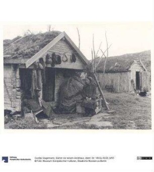 Samin vor einem Holzhaus