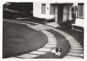 Garten von Dombois, Ermatingen am Bodensee: Vorgarten, gebogener Plattenweg mit Hund