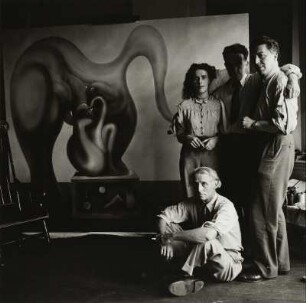 Max Ernst (sitzend), Leonora Carrington, Marcel Duchamp und André Breton (stehend) vor dem Bild von Max Ernst "Der Surrealismus und die Malerei"
