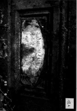 Grabstein 18 (Index: 100109230) Material: Sandstein mit weißer Marmorplatte Zustand: Stele fehlt, Sockel und Platte leicht verwittert Beschreibung: nur Sockel erhalten, Schriftplatte mit Segmentbogen: Grabstein 18A