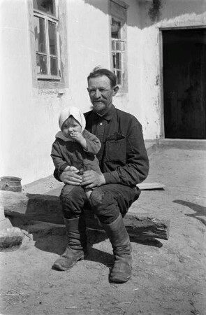 Zweiter Weltkrieg. Zur Einquartierung. Sowjetunion. Großvater mit Enkeltochter, vor einer Bauernhütte sitzend