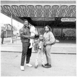 Afroamerikanische Familie mit Kind, im Hintergrund leerer Jahrmarkt (Sonderthema: Familien-Bilder)