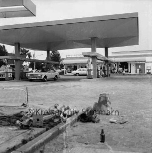 Aral Tankstelle: Hamburger Straße: in der Mitte Zapfsäulen mit Pkws: dahinter Verkaufsraum: hinten links Wohnhäuser: vorn links kleine Baustelle mit Kabeln, Metallteilen und Zementblock
