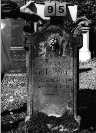 Grabstein 95 (Index: 99792631) Material: sandstein, weiße Marmorinkrustationen Zustand: leicht verwittert Maße HxBxT: 107x45x18 cm Beschreibung: Stele, eingezogener Giebelartiger Abschluß mit Eckakroteren Symbolik: Blumenstrauß, Ranken: Grabstein 95