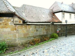 Kirchhof im Westen mit Kirchhofmauer (Wehrgang im 18-19 Jh abgetragen) sowie im 18 Jh im Außenbreich angebaute Pfarrgebäude