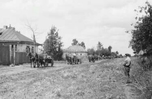 Zweiter Weltkrieg. Frontbilder. Sowjetunion. Konvoi der deutschen Wehrmacht mit Pferdefuhrwerken beim Passieren eines Dorfes