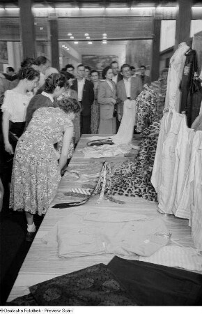Besucher der Leipziger Herbstmesse 1954 beim Betrachten von Damen- und Herrenbekleidung