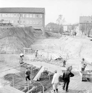 Erweiterungsbau [später Gebäude C] mit Kreistagssitzungssaal: IV. Bauabschnitt: Baugrube an der Reimer-Hansen-Straße: Erstellen der Fundamente für den Kreistagssitzungssaal: vorn Bauarbeiter in Baugrube: im Hintergrund links Erweiterungsbau II. Bauabschnitt