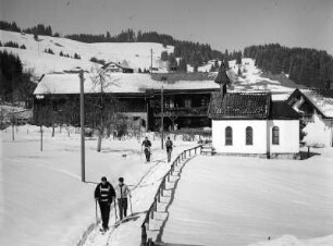 Winterbilder. Ortsteilansicht mit Kapelle und Skiläufern