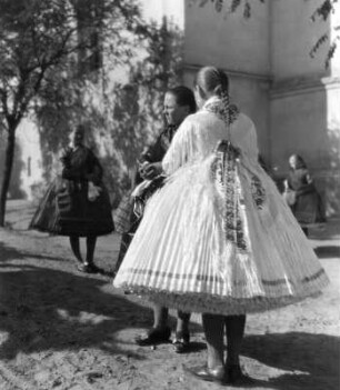 Reisefotos. Mädchen vor der Kirche in Trachten mit weiten Röcken (wahrscheinlich in Csömör)