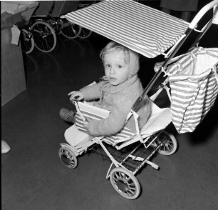 Kleinkind in einem Kindersportwagen mit Sonnendach. Aufnahme in einem Fachgeschäft für Kinderwagen