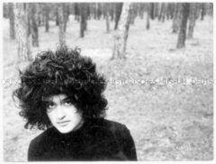 Junge Frau mit schwarzer Perücke vor einem Waldstück (Altersgruppe 14-17)