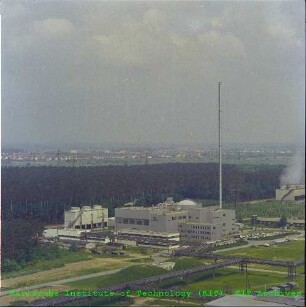Blick vom Abluftschornstein des Forschungsreaktors 2 (FR 2) auf die Kompakte Natriumgekühlte Kernenergieanlage (KNK) mit den umliegenden Betriebsgebäuden, von Südosten